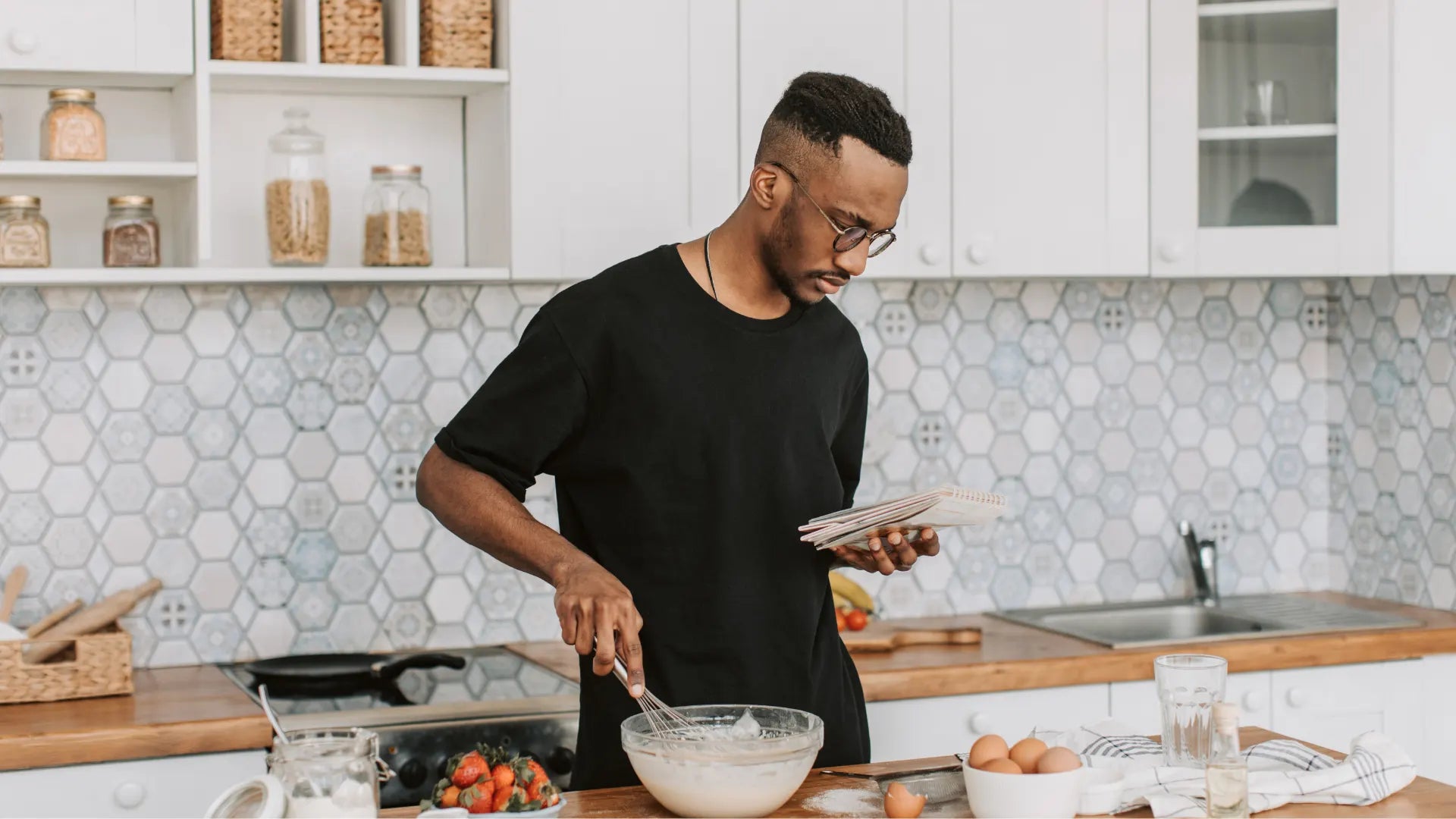 Person mixing ingredients in a kitchen while preparing baked goods.